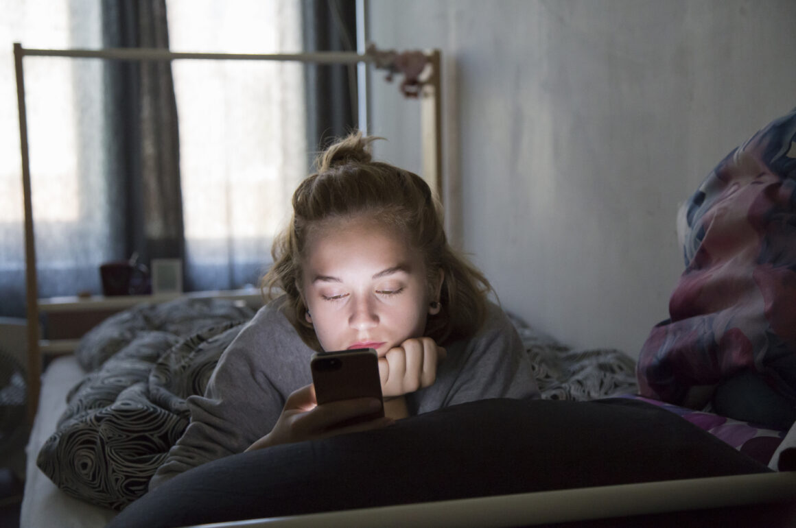teenage girl on phone in bedroom